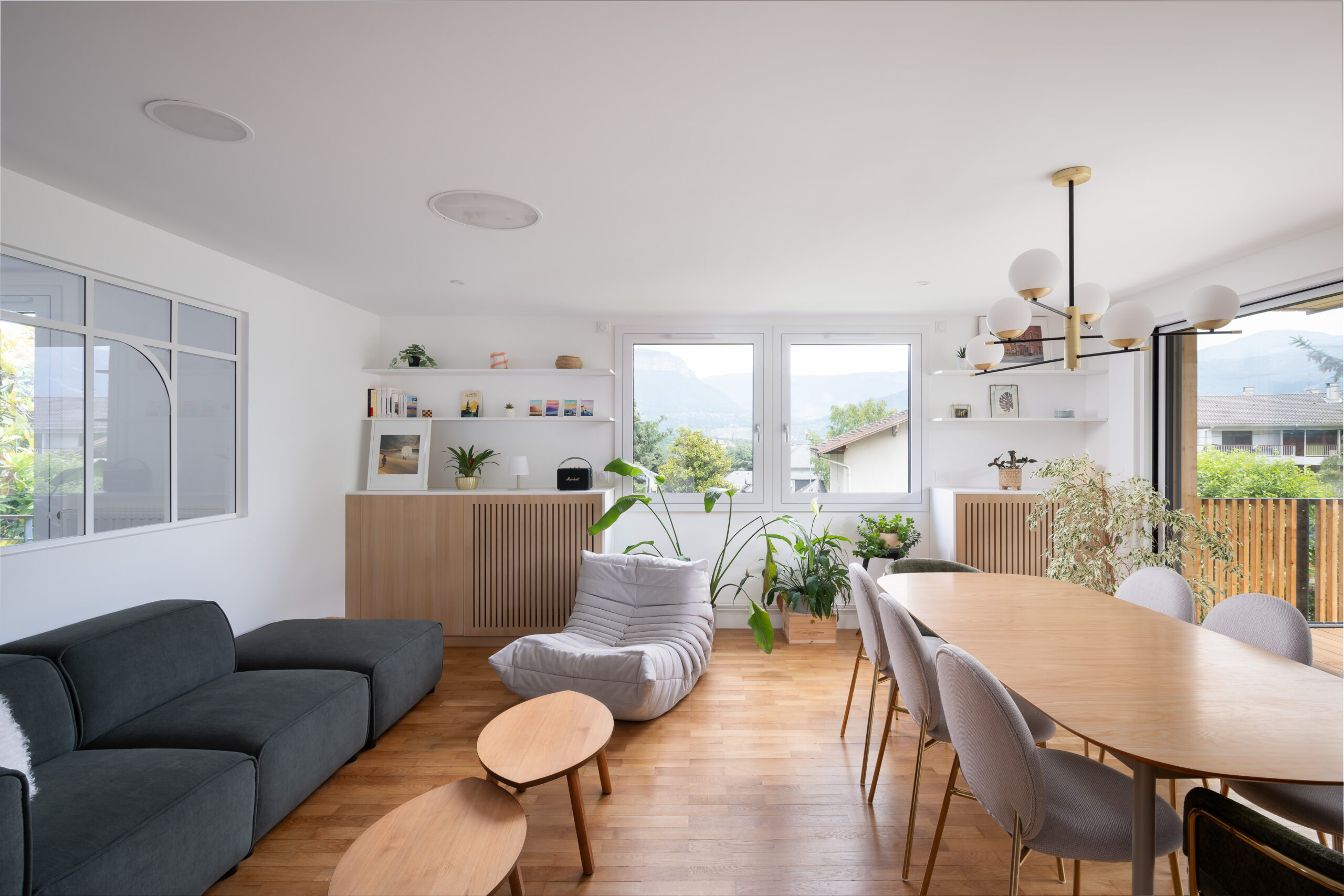 Ameublement et décoration d'intérieur de ce salon séjour composé d'un mobilier moderne et confortable associant des matériaux naturels comme le bois à des matières élégantes comme le laiton des suspensions.